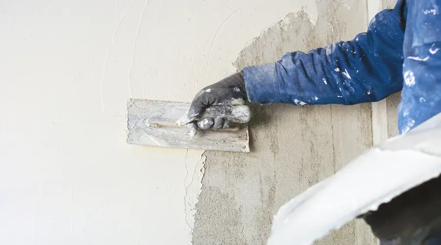 person applying plaster to wall
